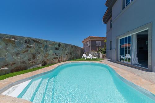 a swimming pool in a yard next to a house at Villa Edén House by Maspalomas Holiday Villas in Maspalomas