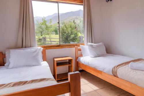 two beds in a room with a window at San Francisco Lodge in Los Andes