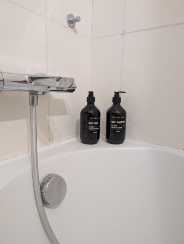 2 bouteilles noires assises au bord d'une baignoire dans l'établissement La parenthèse azuréenne, à Cagnes-sur-Mer