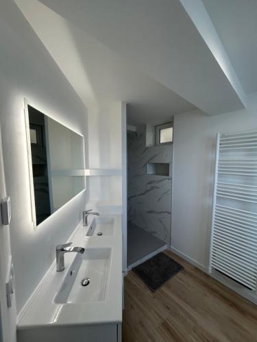 une salle de bain blanche avec un lavabo et un miroir dans l'établissement Maison T3 proche MER - Ideal en famille ou entre amis, à La Forêt-Fouesnant