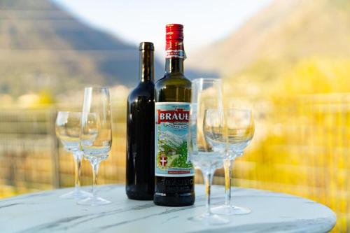 two bottles of wine and three wine glasses on a table at GIULY Apartment in Aprica