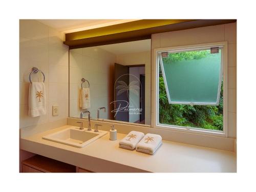 a bathroom with a sink and a large mirror at Palmares, Casa de praia in Búzios