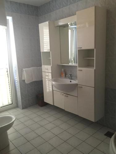 a white bathroom with a sink and a mirror at Apartments Antonia in Malinska