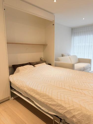 a bedroom with a large bed with a chair and a window at Studio Nacre Knokke in Knokke-Heist