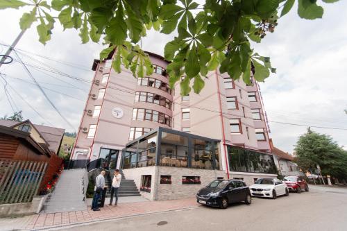 a pink building with cars parked in front of it at Hotel Dorna in Vatra Dornei