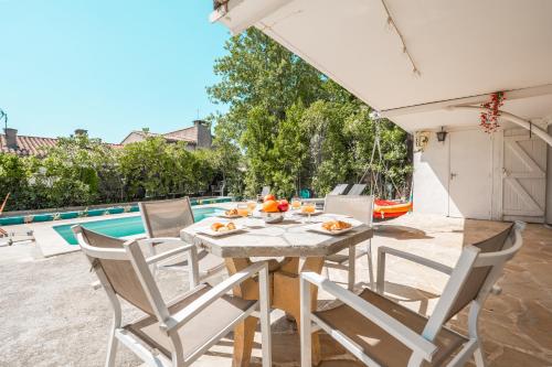 un patio avec une table et des chaises et une piscine dans l'établissement Ambiance sudiste , piscine, boule, farniente AG, à Carcassonne