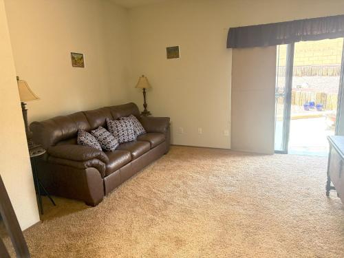a brown leather couch in a living room with a window at Casa Herradura Near Petroglyphs in Albuquerque