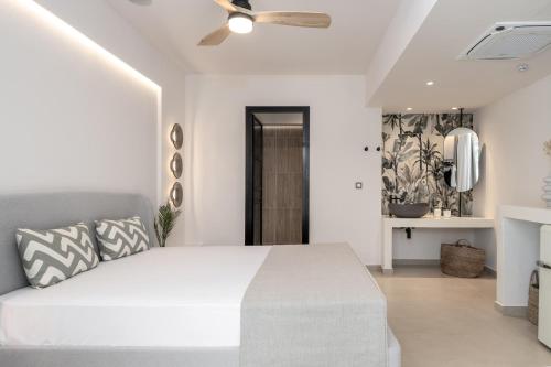 a white bedroom with a bed and a ceiling fan at Socrates Apartments in Skala Kefalonias