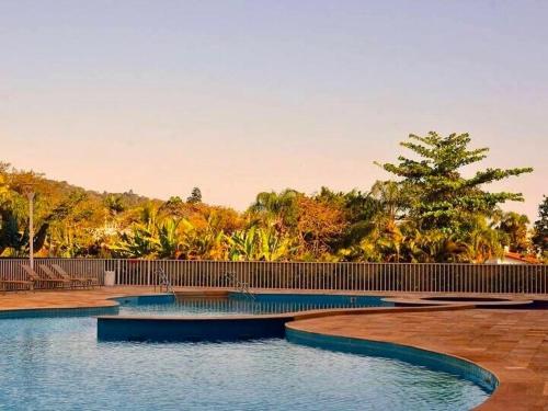 een zwembad met een hek en bomen bij Condôminio Latitude 23 - Ubatuba in Ubatuba