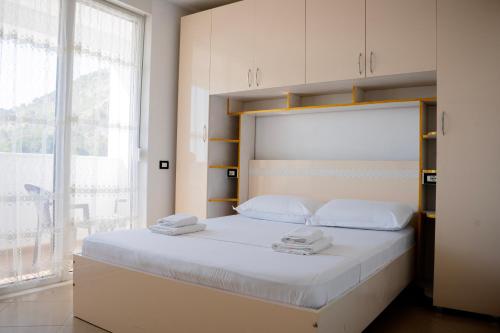 a bedroom with a large white bed with towels on it at Liora Seaview Apartments in Shëngjin
