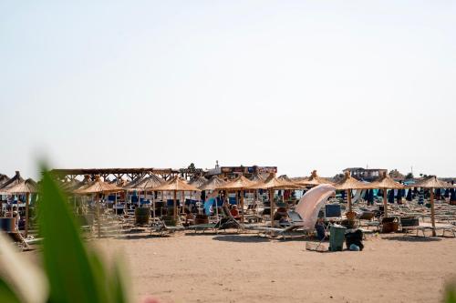 a beach with umbrellas and chairs and people on the beach at Liora Seaview Apartments in Shëngjin