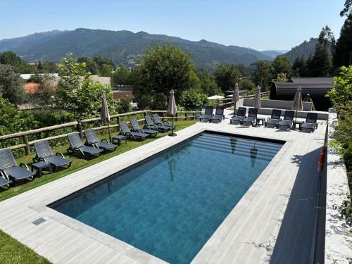 a swimming pool with chaise lounges and chairs at Gerês Wood Valley in Geres