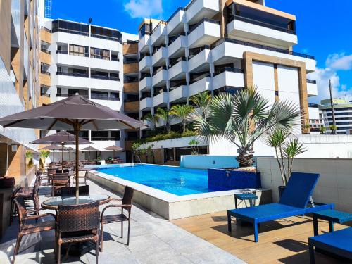 a swimming pool with chairs and tables and a building at Aptos super confortáveis no Gold Flat by Apartamentos Jampa in João Pessoa