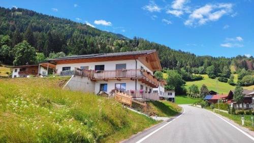 a house on the side of a hill next to a road at Ferienwohnung Alpy in Schlaiten