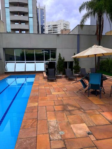 basen z krzesłami i parasolem obok budynku w obiekcie Barbosa Studios - Bela Cintra w São Paulo