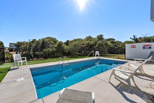 a swimming pool with two chairs next to at Serenity Shores in Southern Shores