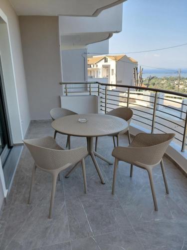 Un patio con una mesa y sillas en un balcón. en Theasis Deluxe, en Lefkada