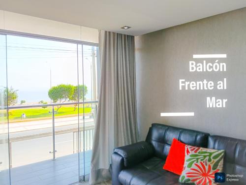 a living room with a leather couch and a large window at FRENTE AL MAR en SAN MIGUEL Apartamento LIMA CHECK IN in Lima