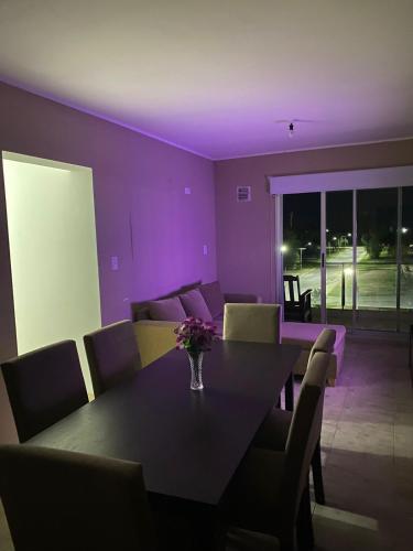 una sala da pranzo con tavolo, sedie e illuminazione viola di Cielo Apart- Departamento Céntrico a San Luis