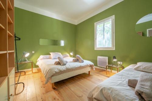 ein grünes Schlafzimmer mit 2 Betten und einem Fenster in der Unterkunft Chez papy Charles in Carcassonne