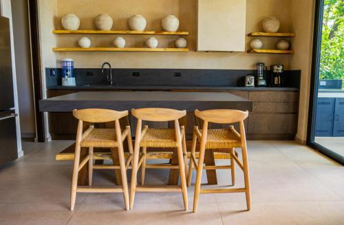 a kitchen with a counter with four chairs around it at Casa Lagom, Luxurious Oasis with Infinity Pool! in La Cruz