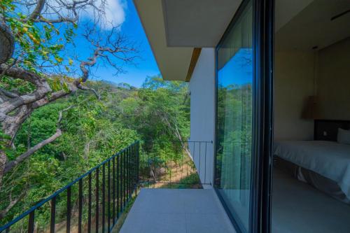 a bedroom with a balcony with a view of the forest at Casa Lagom, Luxurious Oasis with Infinity Pool! in La Cruz