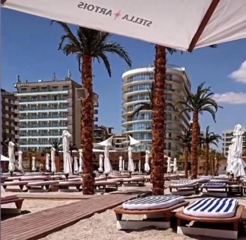 a row of chaise lounges on a beach with palm trees at White Luxury Apartament in Mamaia Nord