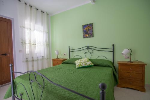 a bedroom with a green bed with a green comforter at Grappolo B&B affittacamere in Ascea
