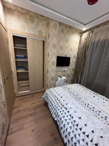 a bedroom with a white bed and a tv at Studio proche clinique akdital ain sebaa in Casablanca