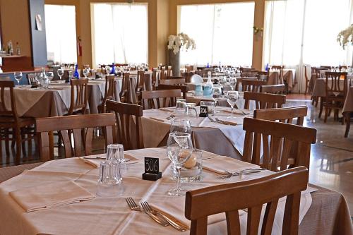 a dining room with tables and chairs with white table linen at Hotel La Fenice in Lido di Jesolo