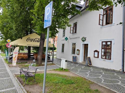 a sign in front of a building with a bench at Apartmány Zámecká in Roudnice nad Labem