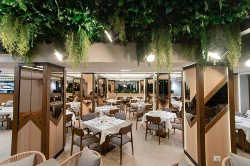 a restaurant with white tables and chairs and plants at Hotel Dorna in Vatra Dornei