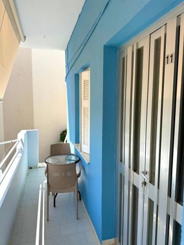 a small balcony with a table and a blue wall at Eftihia Studios Paleochora in Palaiochóra