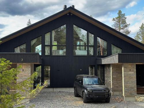 a black house with a car parked in front of it at Black Villa, Aurora View Bath & Sauna, Private Design Villa in Lapland in Kolari