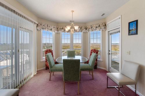 a dining room with a table and chairs and windows at Skippers Landing in Manteo