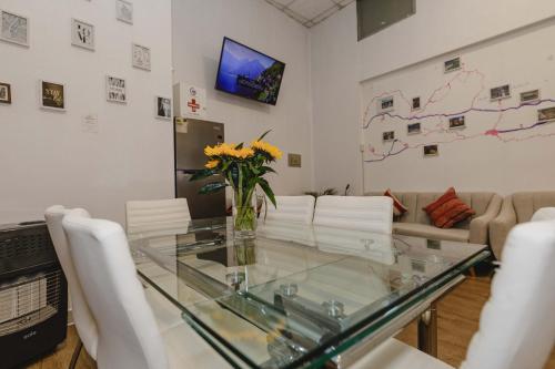 a living room with a glass table and white chairs at Cozy Room Cusco in Cusco