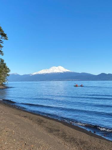 a boat on the water with a snow covered mountain in the background at Calma Cabins in Puerto Clocker
