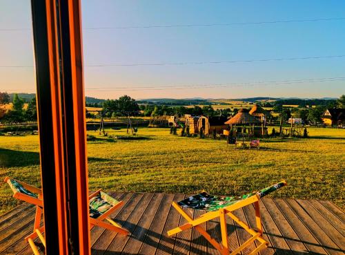 a table on a deck with a view of a field at Glamping Niebiańska Osada Jurty Dolnośląskie & SPA in Polanica-Zdrój
