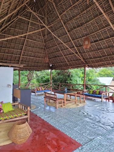 a pavilion with benches under a straw roof at Jabulani House Rooms in Kendwa