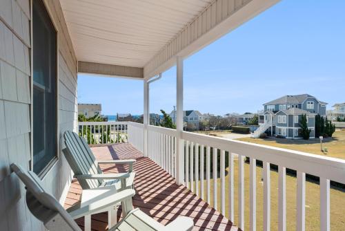 two chairs on a porch with a view of the ocean at Slumbering Duck in Sanderling