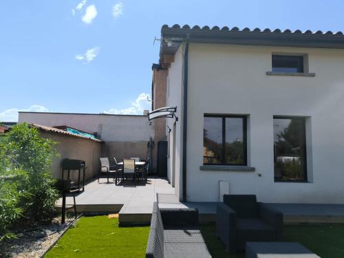 a white house with a patio with a table and chairs at Mi Amore- Gîte 3 suites près de Lyon, parking free in Pizay