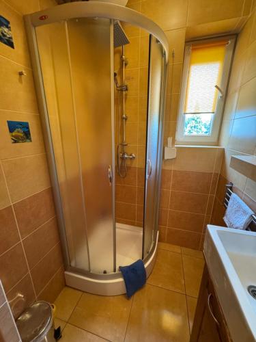 a shower with a glass door in a bathroom at Gościniec Grek Zorba - pokoje i domki 4 osobowe - 16km od Zator Energylandia in Inwałd
