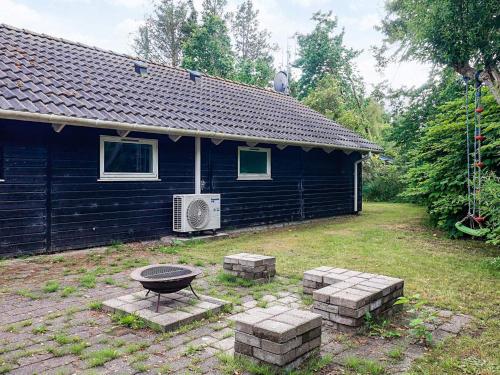 a black house with a grill in the yard at 6 person holiday home in Asaa-By Traum in Aså
