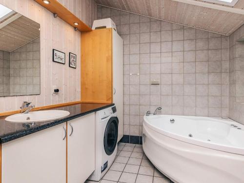 a bathroom with a tub and a sink and a washing machine at 6 person holiday home in Hadsund in Hadsund