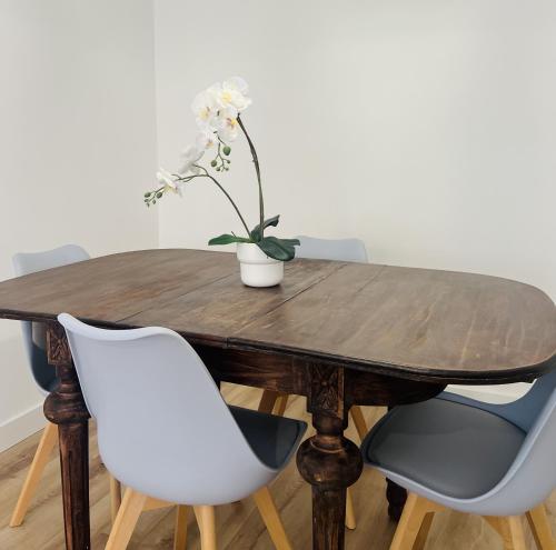 a wooden table with chairs and a vase with flowers on it at Leña II - by Wehomes - Pleno centro in Santander