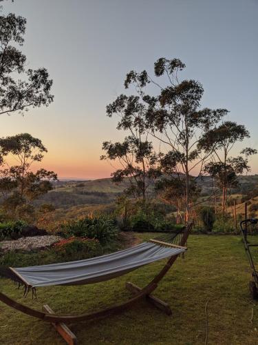 a hammock in a field with the sunset in the background at Maleny-Montville Cottages #1 - 2 bed ocean views in Balmoral Ridge
