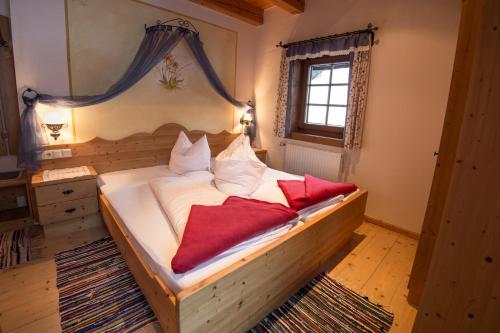 a bedroom with a bed with white sheets and red pillows at Familienwanderhof Eggeler in Liesing