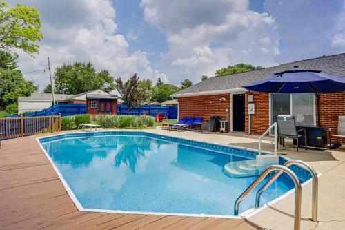 a swimming pool with an umbrella next to a house at Dayton Family Home with Game Room Walk to City Park in Dayton