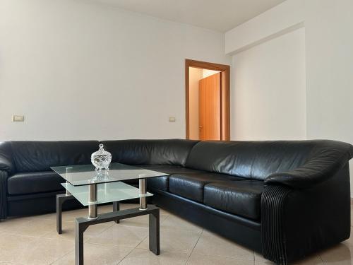a black leather couch with a glass table in a living room at New Sea View Apartment Lungomare in Polisi i Vogël