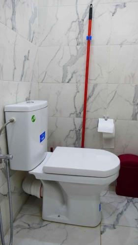 a white toilet in a bathroom with a red pole at Appartement Sabah A Essaouira in Ghazoua